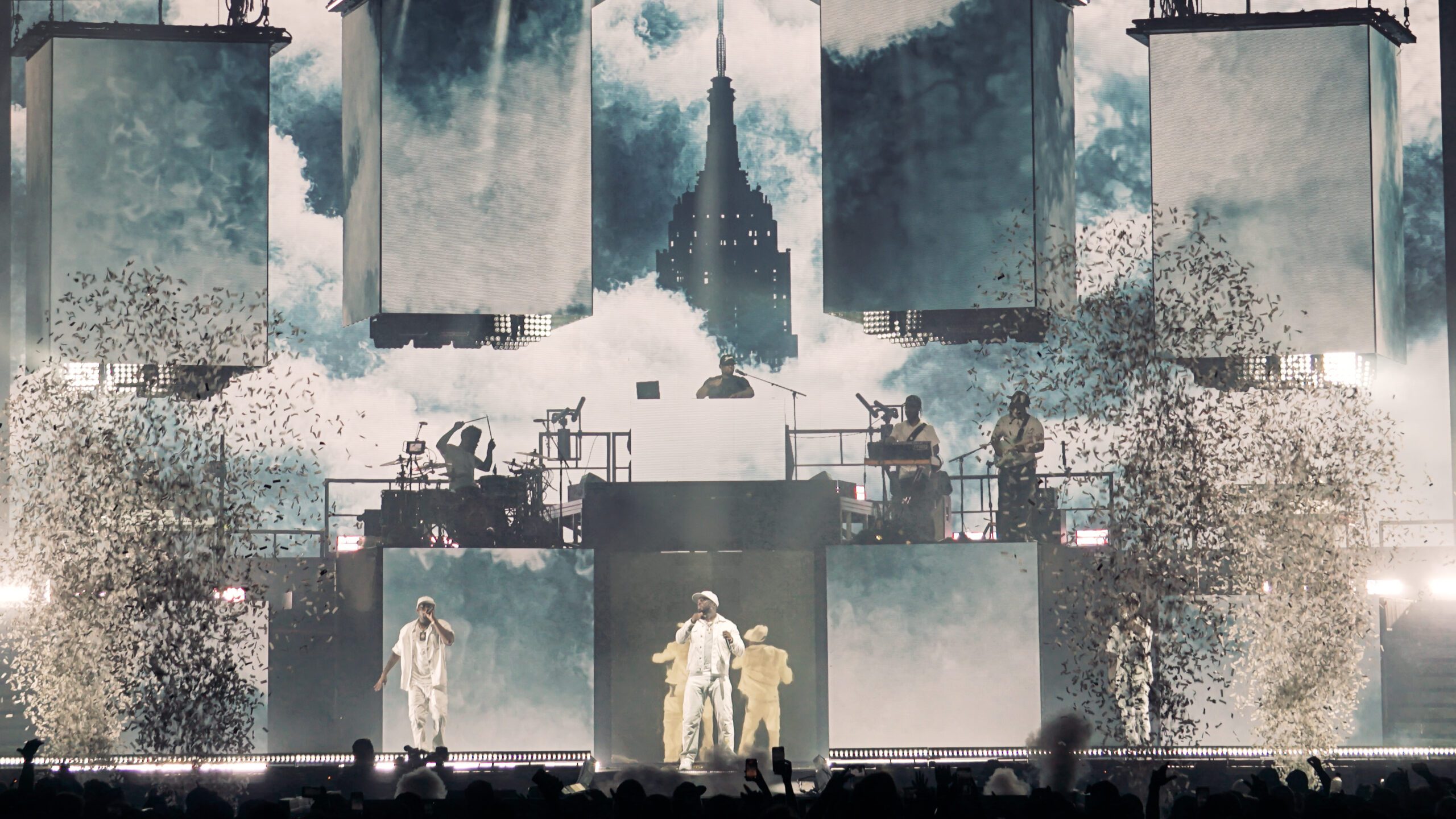 The Empire State Building rising through clouds as confetti falls on stage