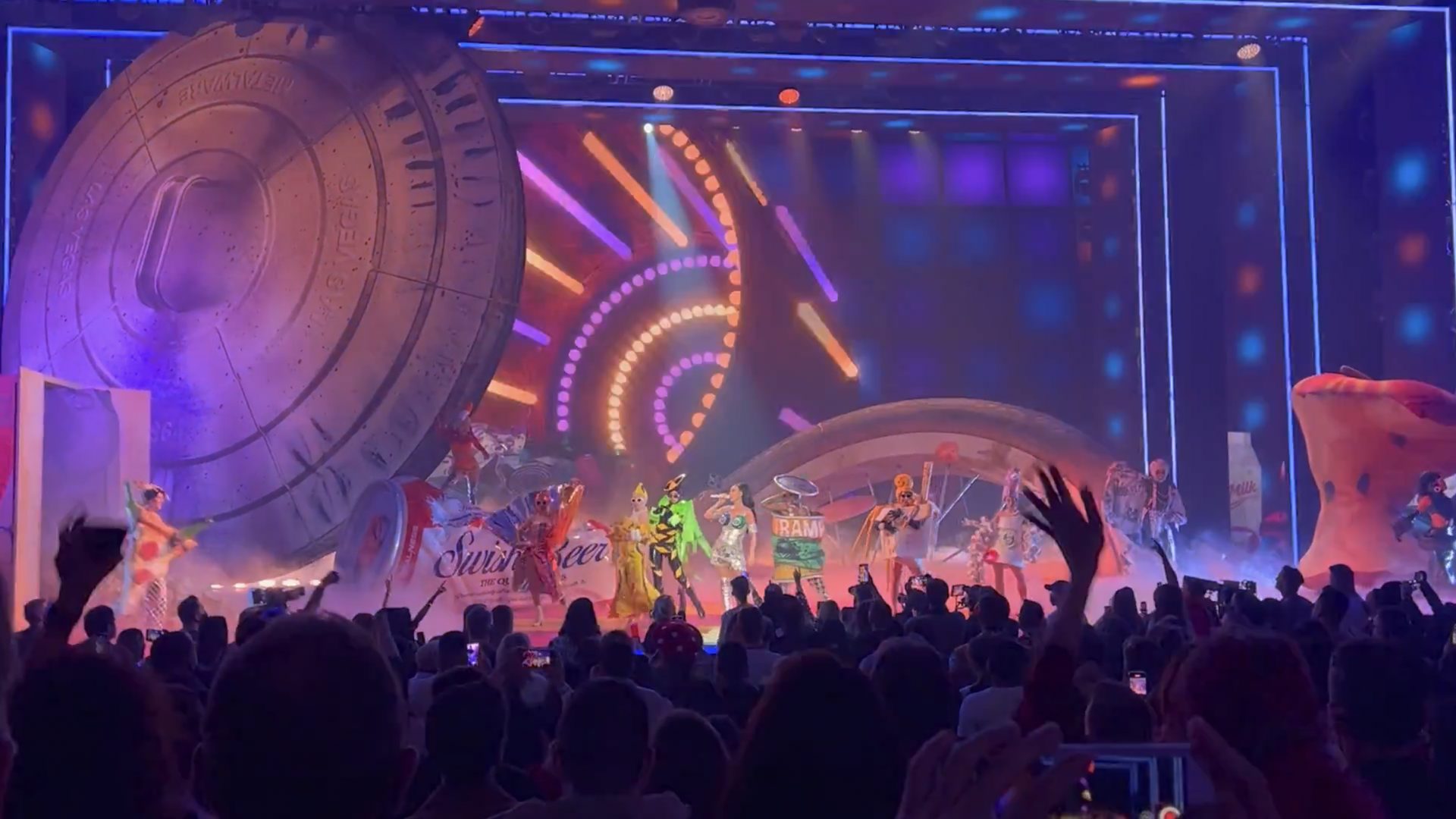 Wide view of the PLAY stage with neon light rings and giant props