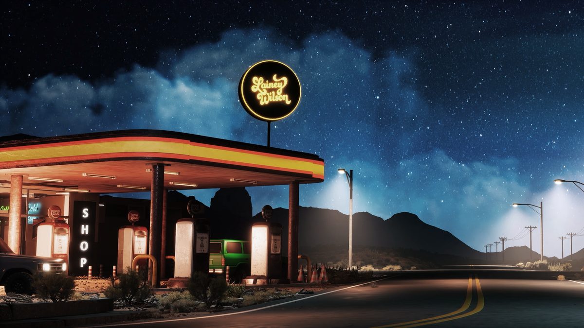 Lainey Wilson tour visual: a roadside gas station at night under a neon Lainey Wilson sign