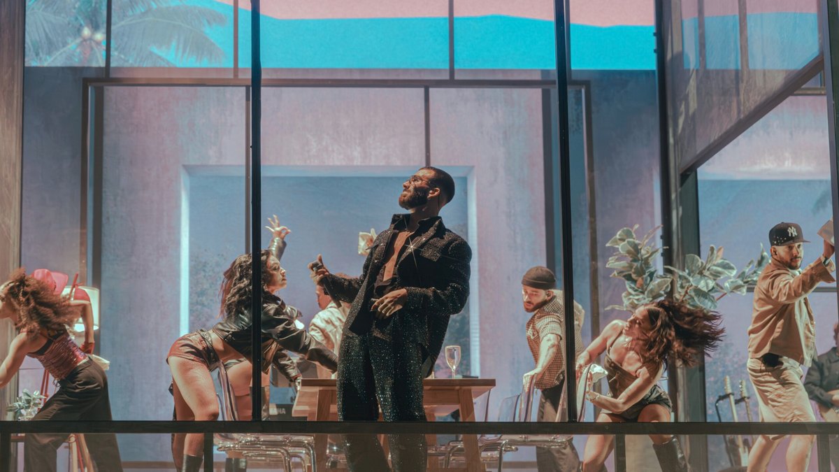 Manuel Turizo show visual: Manuel Turizo and dancers inside the glass house against a pastel blue sky