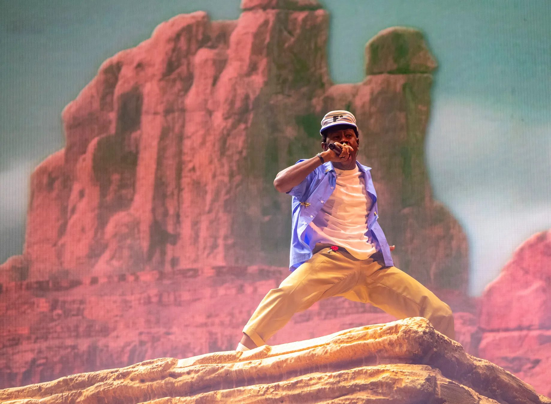 Tyler, the Creator performing on a rock in front of towering red buttes on the LED wall