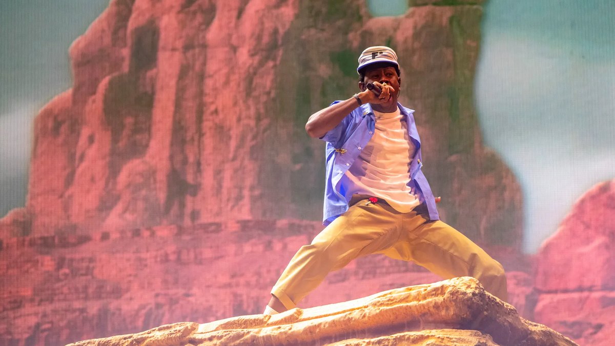 Tyler, the Creator performing on a rock in front of towering red buttes on the LED wall